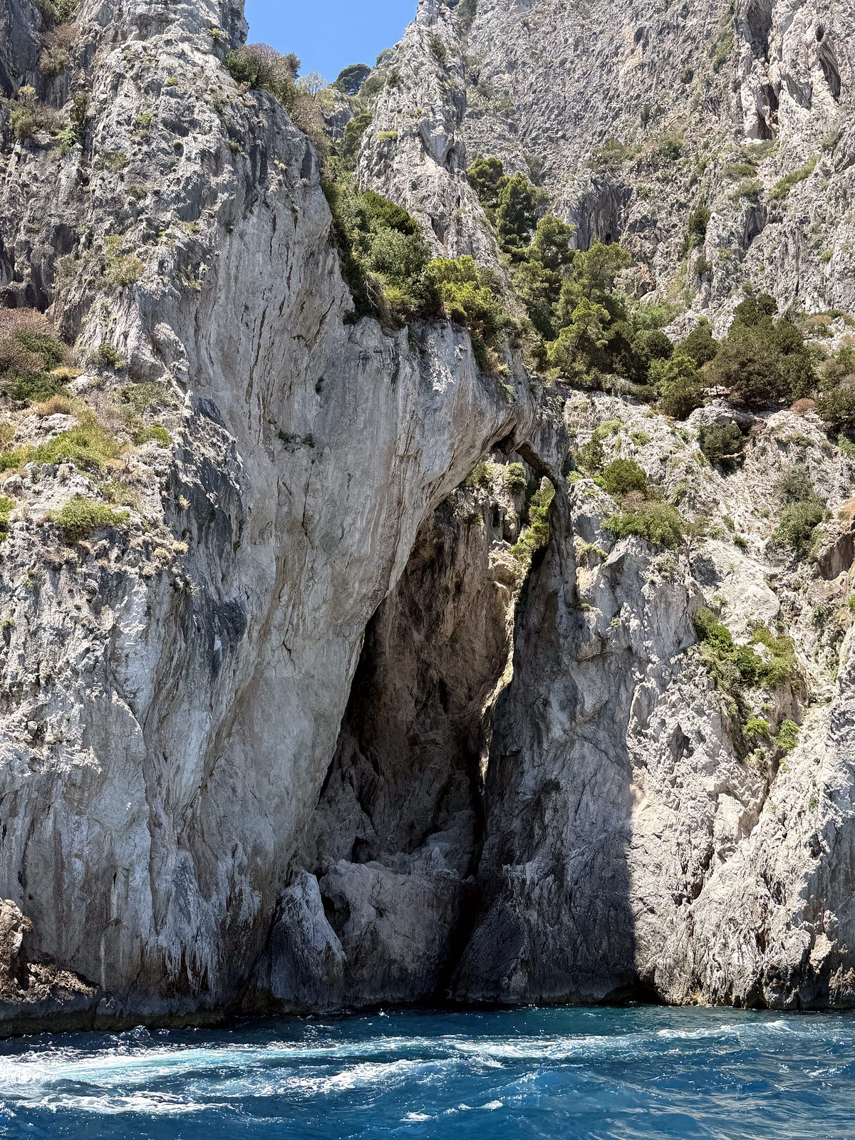 A boat passing under the Faraglioni arch