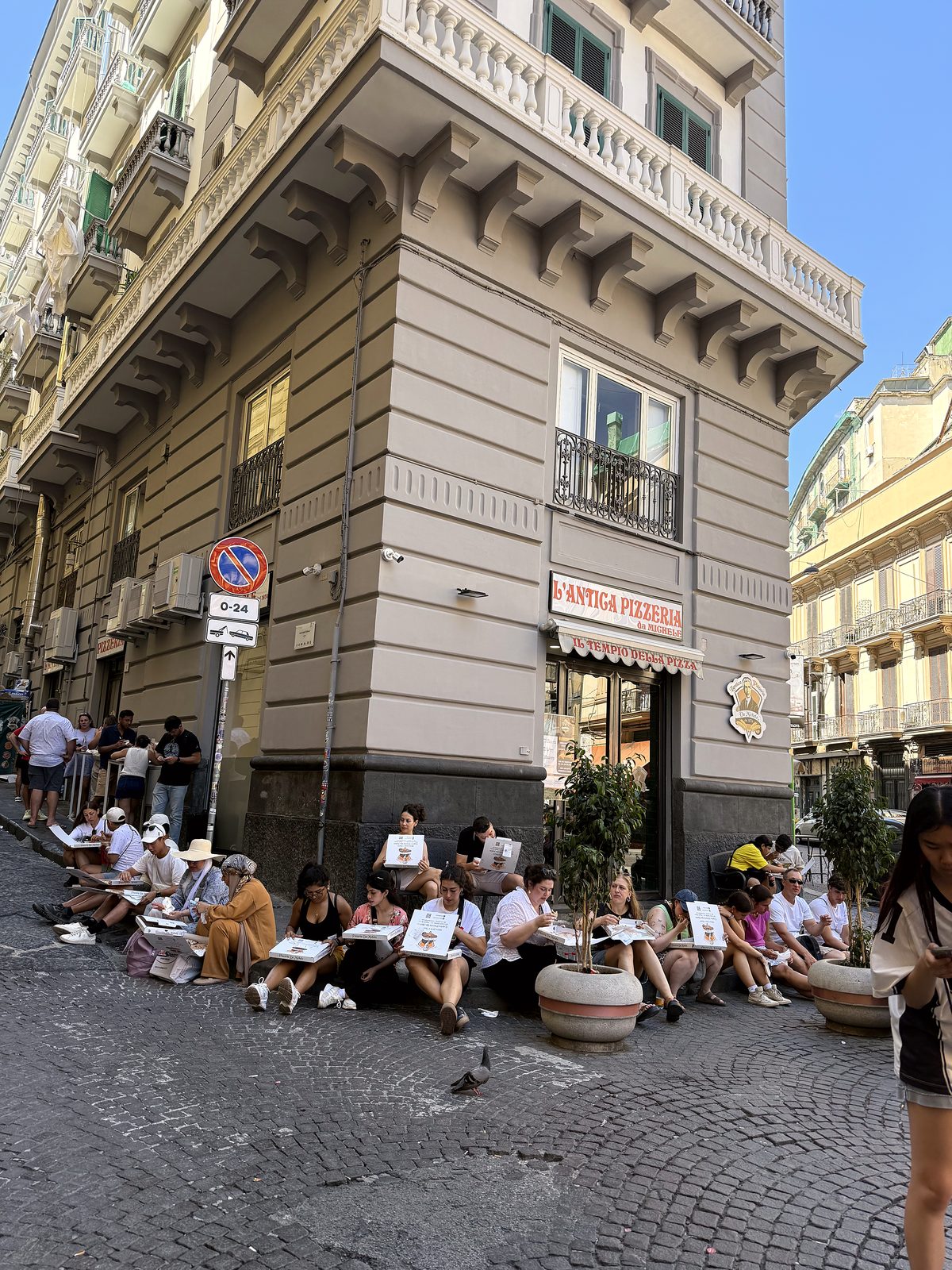 People eating pizza on the street outside Da Michele