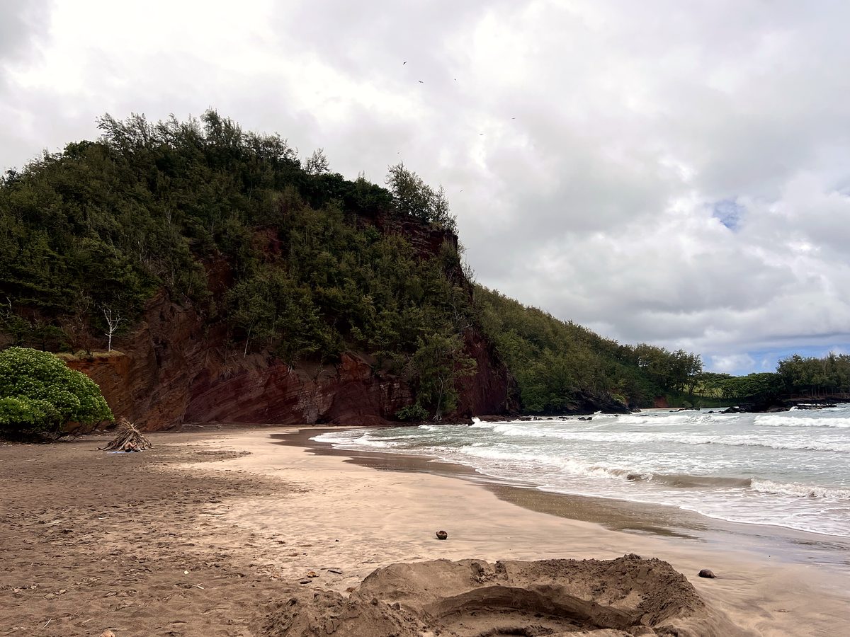 A red-sand cove backed by cliffs on the Hana coast